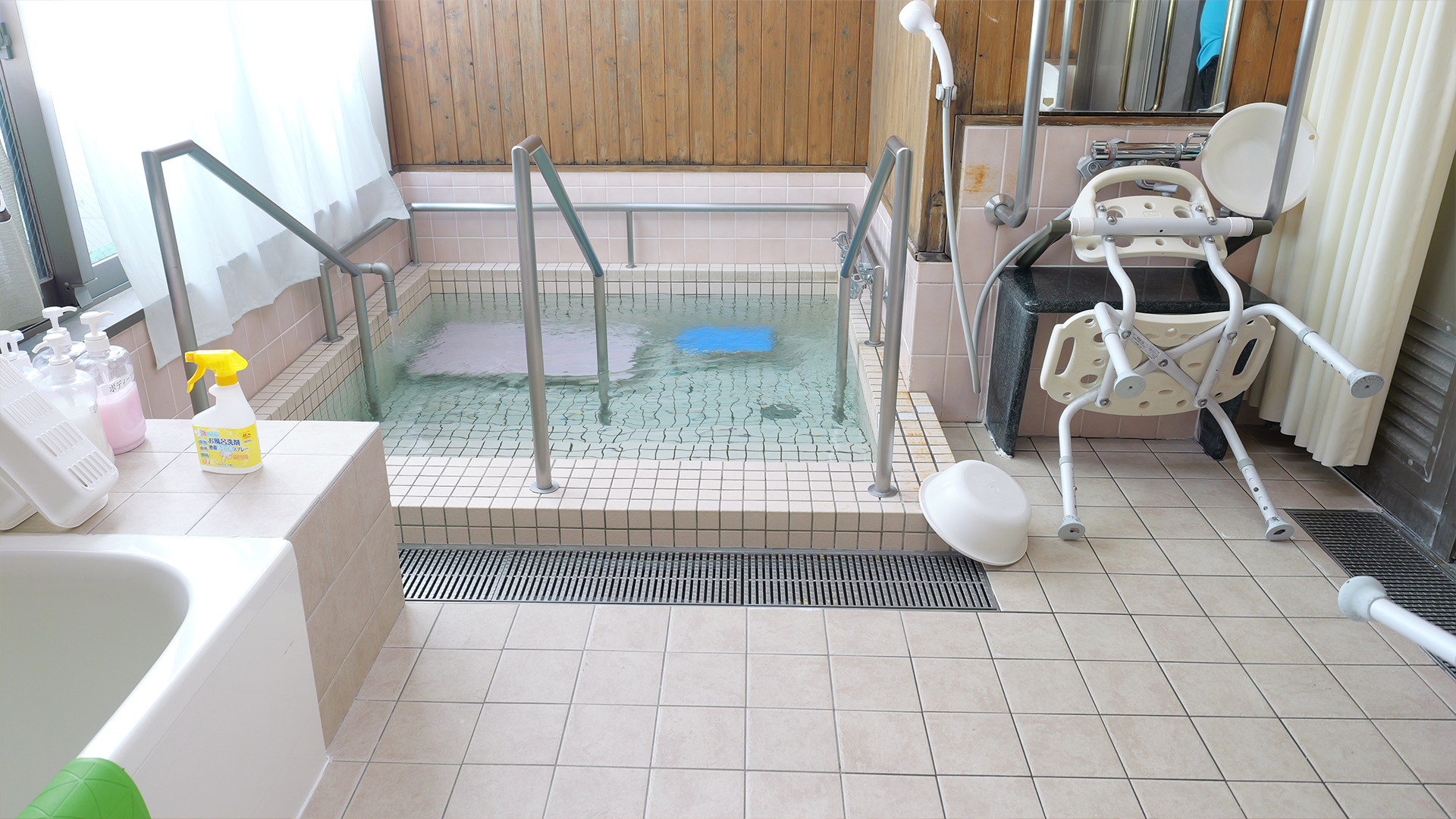 そらりお畦野の大浴場入口側（入浴補助チェアと手すり）